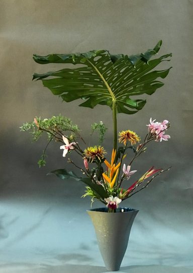 Rikka Shimputai - Démonstration Ikebana Dubaï - Maivan Floral Composition ikebana Rikka Shimputai avec feuille de Monstera et fleurs tropicales dans un vase comique bleu