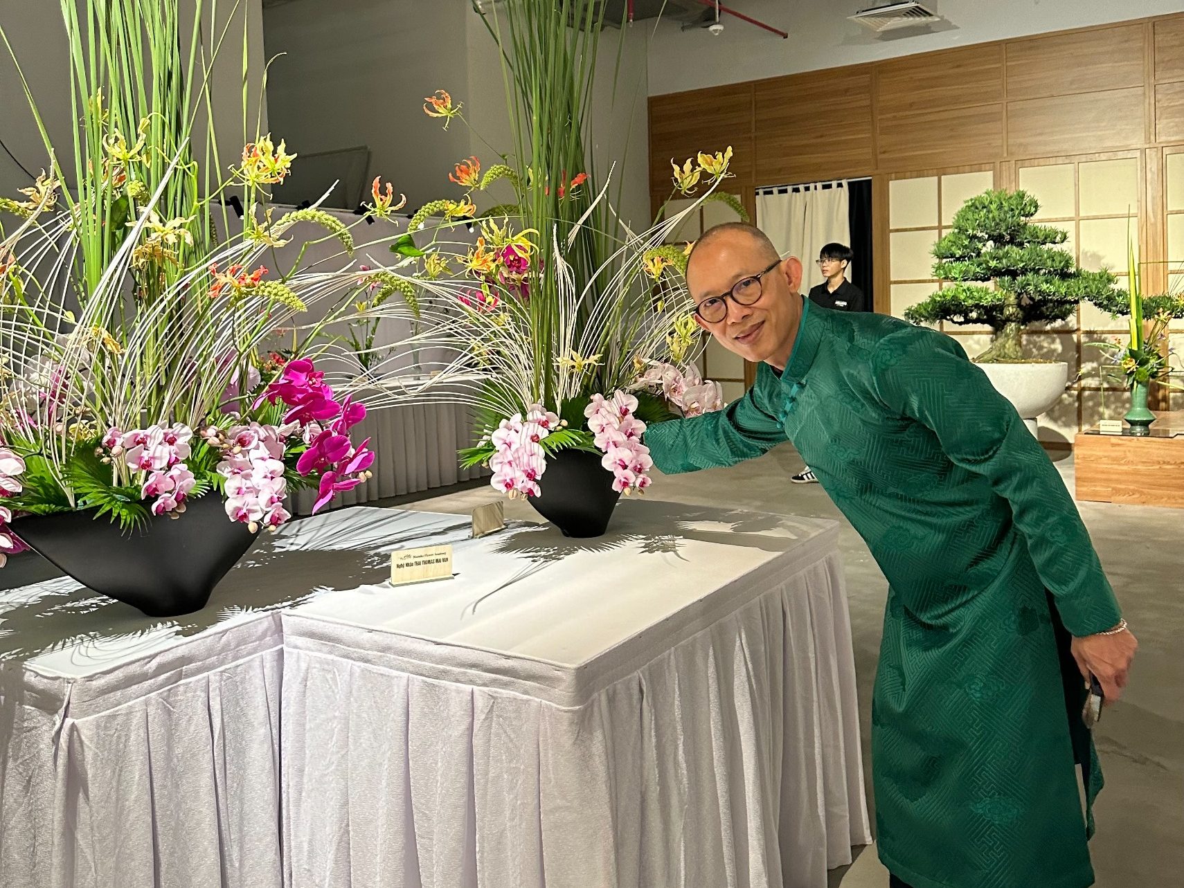 MAI VAN Thai Thomas professeur art floral, ajustant composition aux orchidées Gloriosa lors de l'exposition