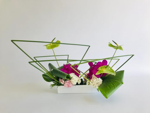 Jiyuka Ikenobo - Maivan Floral Composition Ikebana Jiyuka avec feuillages verts, fleurs fuchsia et blanches, structure géométrique en tiges noires sur fond clair