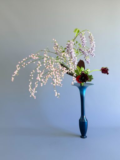 Rikka Shimputai - Arrangement floral japonais - Maivan Floral Composition ikebana Ikenobo avec branches tombantes et roses rouges dans un vase haut et fin